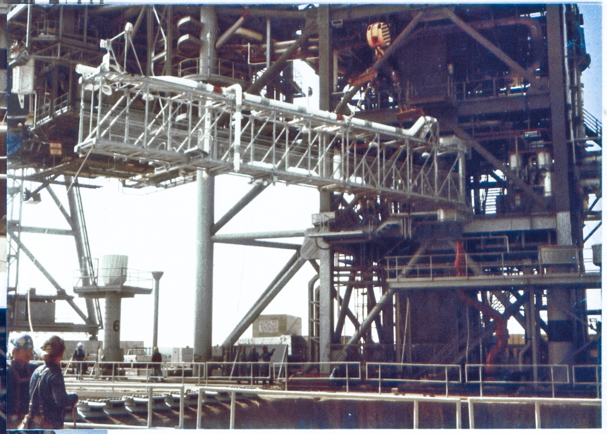 The Gox Arm Truss, partially rotated to its install orientation, gets lifted by the Hammerhead Crane, as Union Ironworkers from Local 808, working for Ivey Steel at Space Shuttle Launch Complex 39-B, Kennedy Space Center, Florida, control the lift and get ready to attach the arm to the top of the Fixed Service Structure. Personnel on the ground, working the lift, including Wade Ivey, owner of Ivey Steel, give a sense of scale to the work area and the work operation itself.